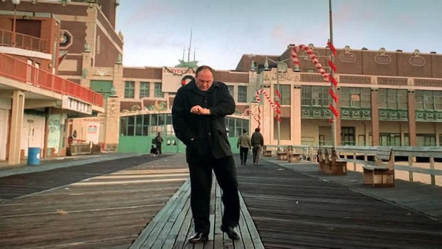 Tony is standing on the boardwalk checking his watch for the time.